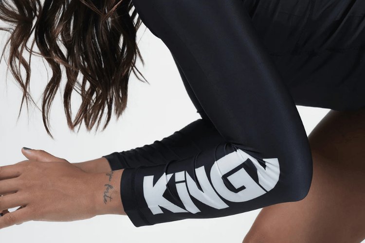 Close-up of an athlete wearing a black KINGZ rashguard with the KINGZ logo printed on the sleeve.